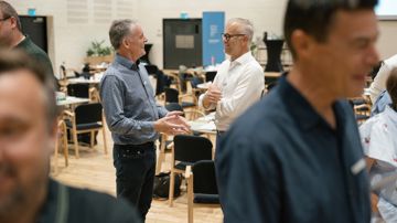 Tillidsrepræsentanterne Allan Danielsen-Boe og Brian Sørensen står på gulvet i en sal i samtale 