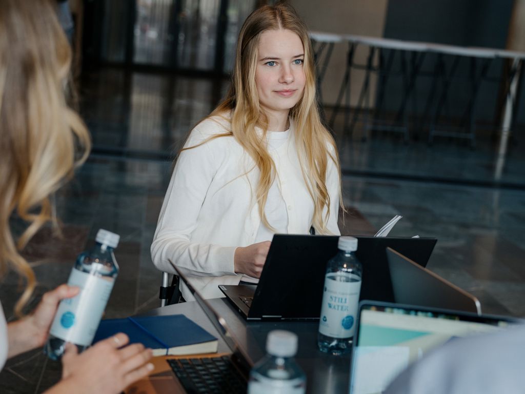 Unge mennesker sidder med computere omkring et bord