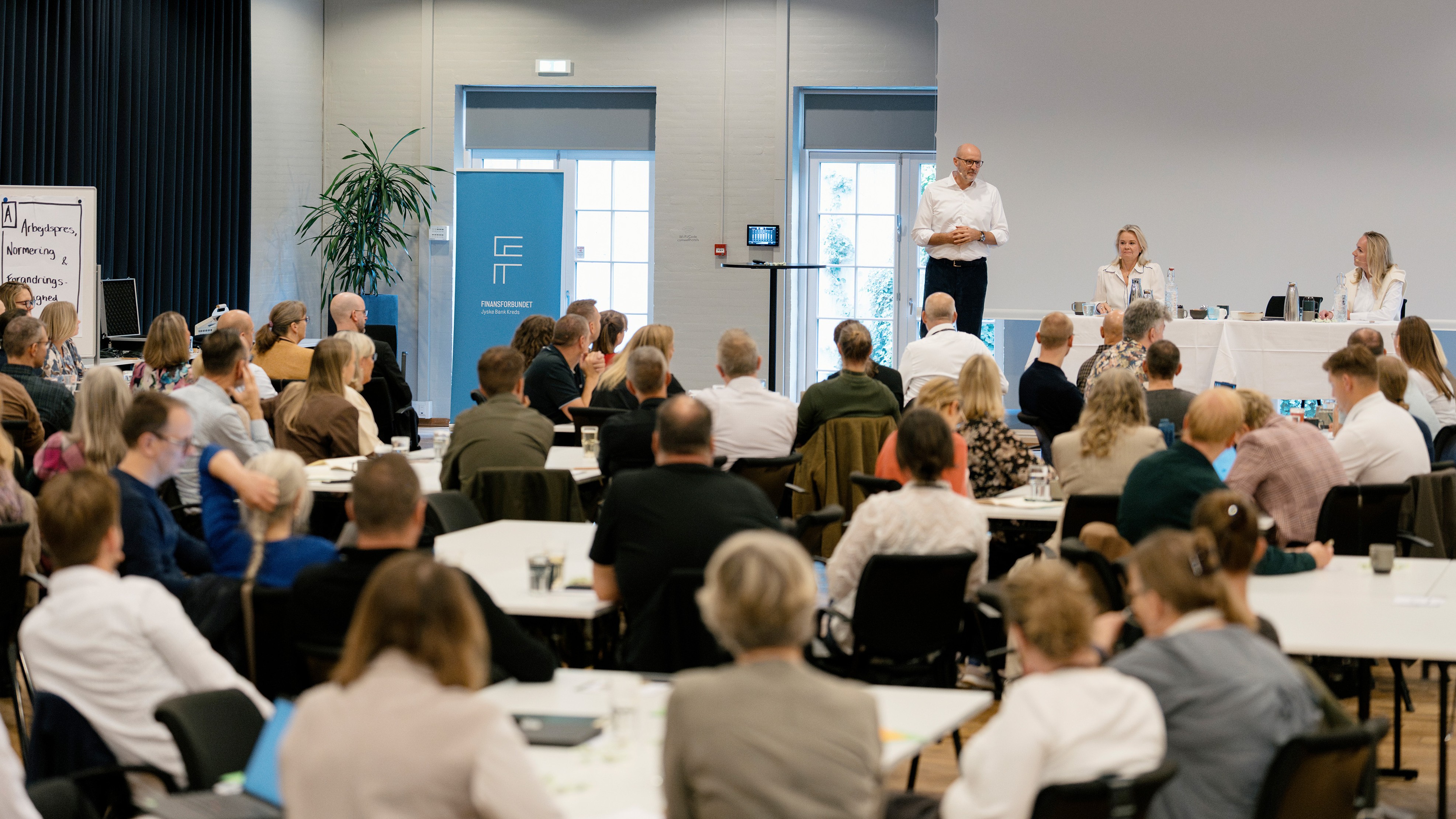 Sal med mennesker der lytter til en person der taler fra podiet