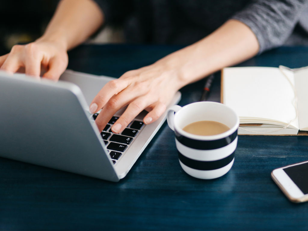 Skrivebord med computer og kaffekop