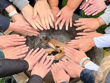Mange hænder ind over et bål