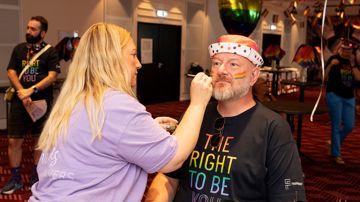 Pride billede, mand bliver malet med ansigtsmaling af kvinde