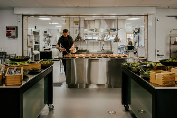Kok forbereder mad i kantine.