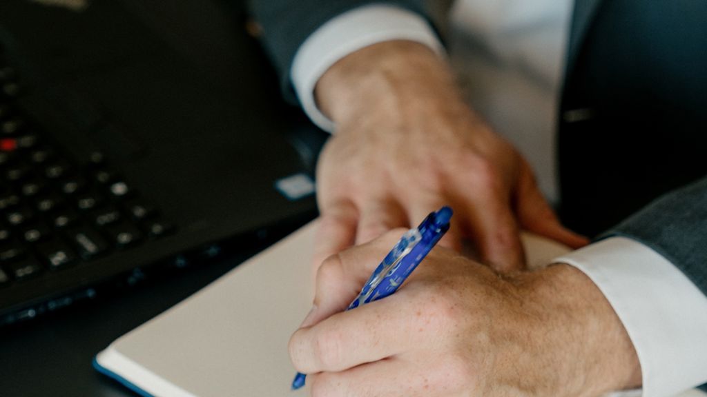 Hænder der holder en kuglepen over en blok