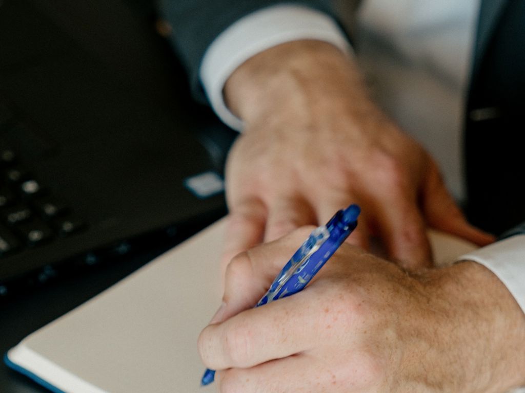 Hænder der holder en kuglepen over en blok