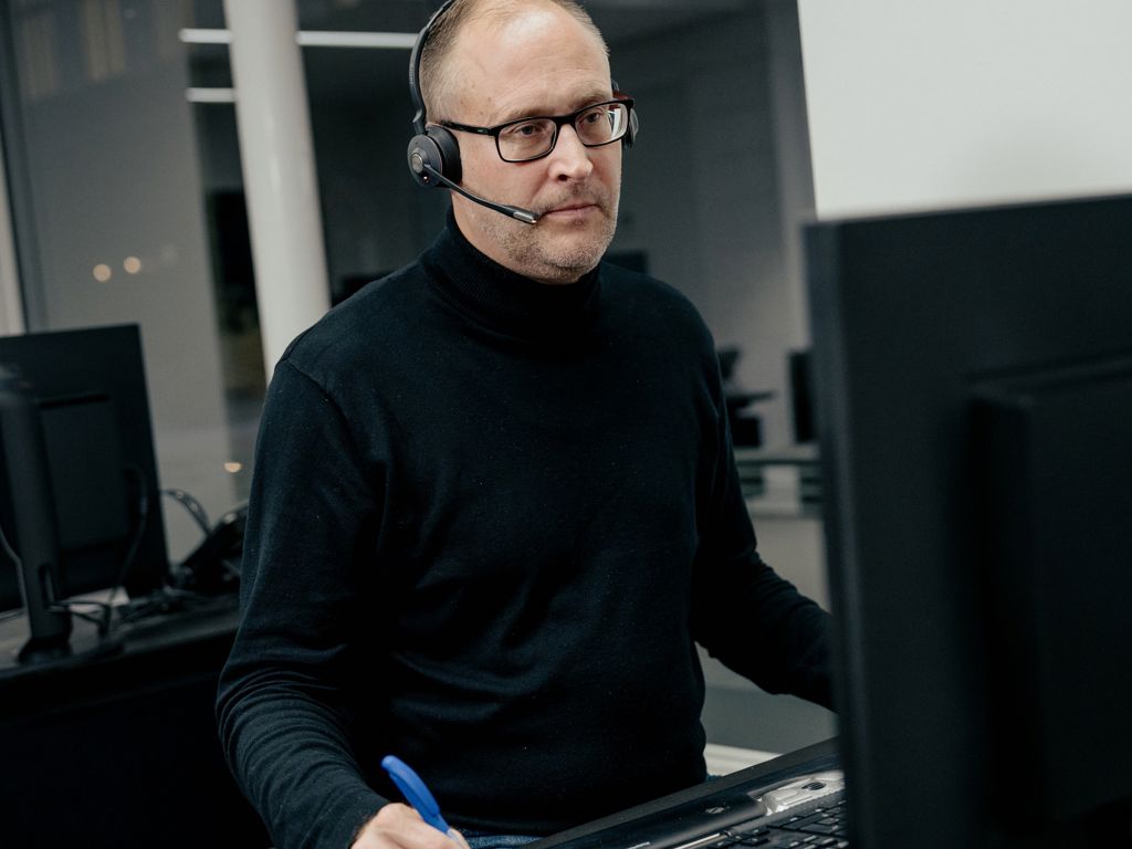 Mand med headset, der kigger på computerskærm