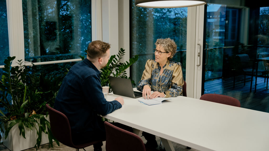 Mand og kvinde har en samtale forenden af et bord 