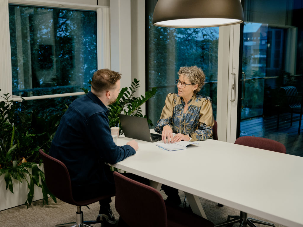 Mand og kvinde har en samtale forenden af et bord 