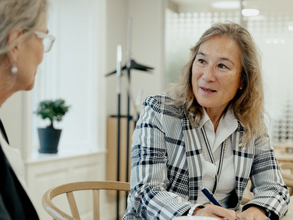 To kvinder sidder ved et mødebord og taler sammen