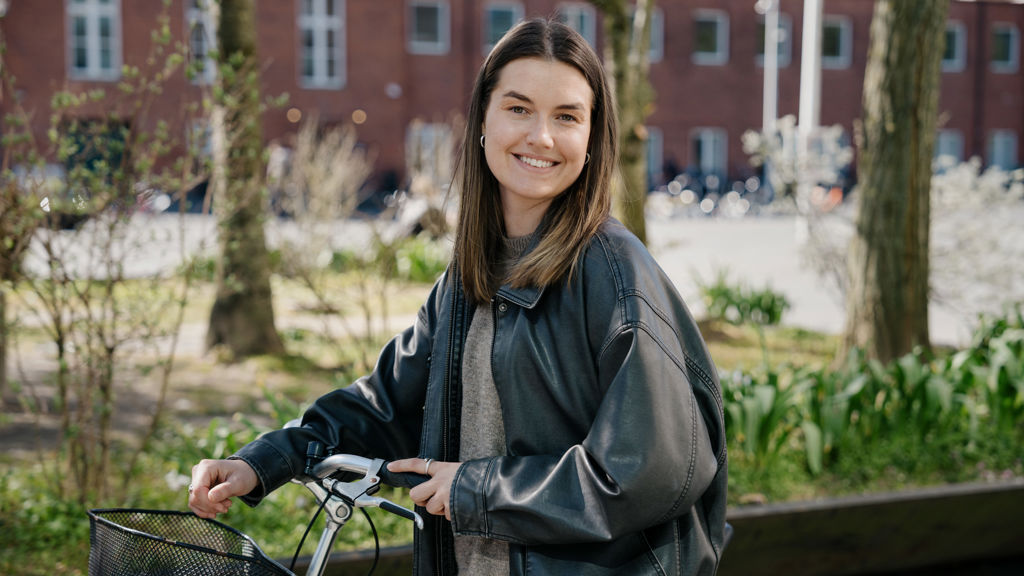 ung pige smiler og står ved sin cykel