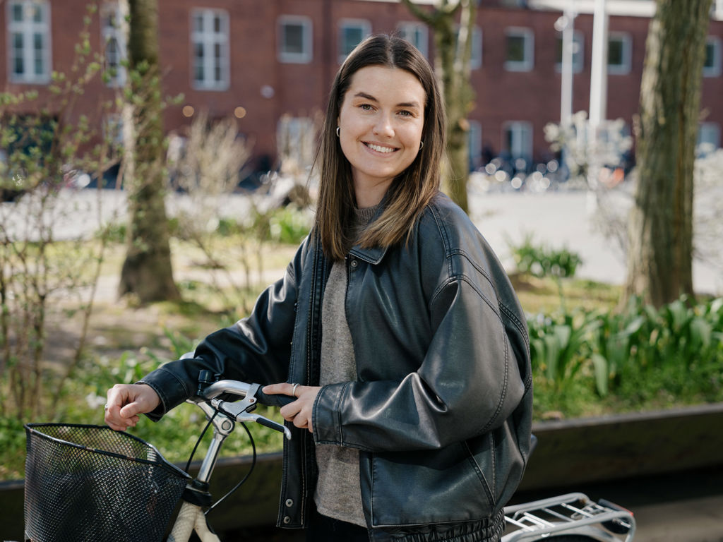 ung pige smiler og står ved sin cykel
