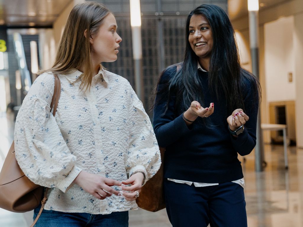 To kvindelige studerende taler sammen, mens de går
