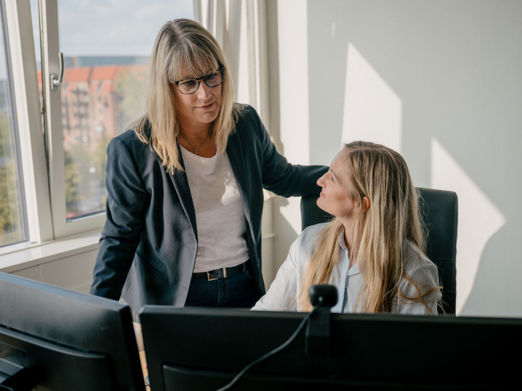 Stående kvinder snakker med siddende kvinde