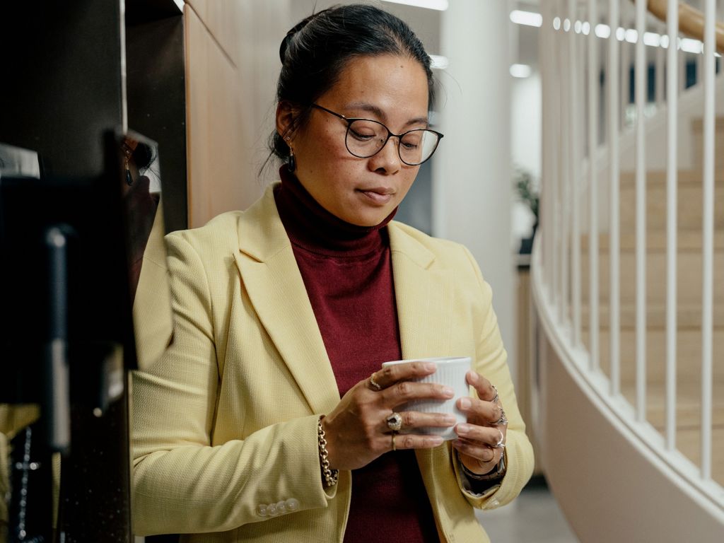Kvinde med kaffekop ved kaffemaskine