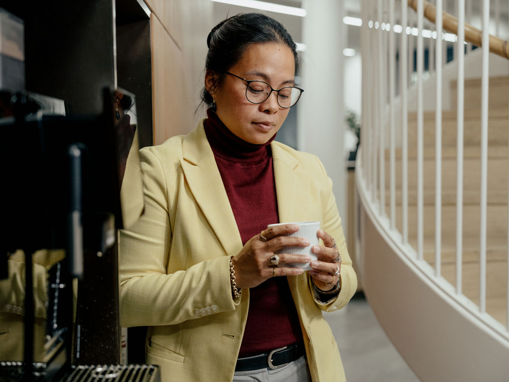 kvinde står og kigger ned i sin kaffekop