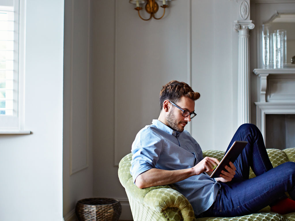 Mand i sofa der arbejder på Ipad