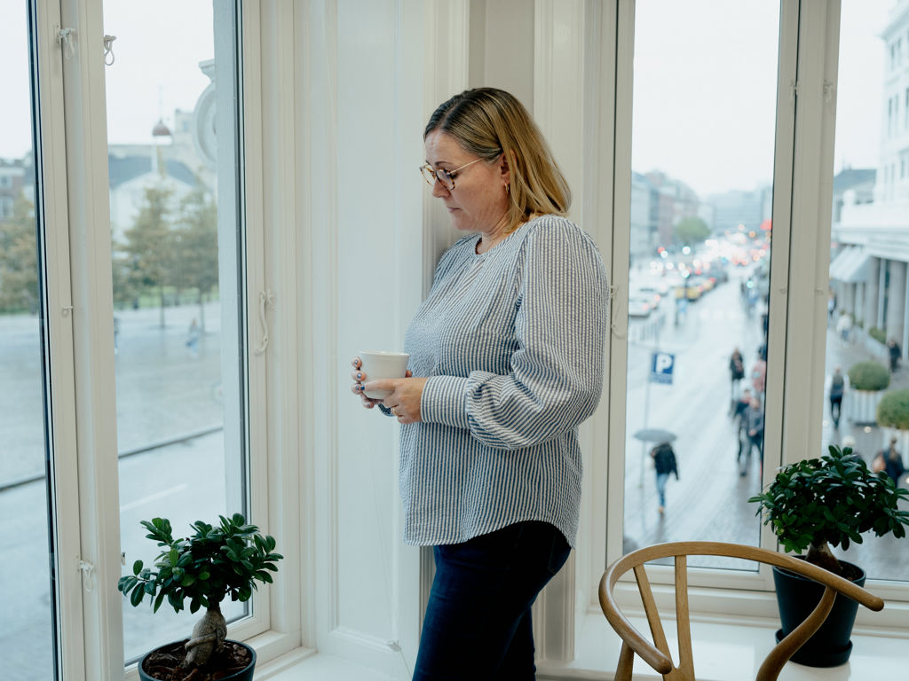 kvinde står ved et vindue og kigger ud