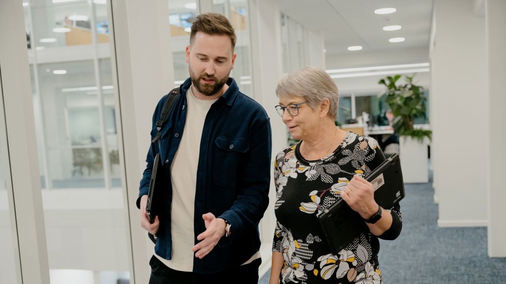 To kollegaer går og snakker på kontorgang