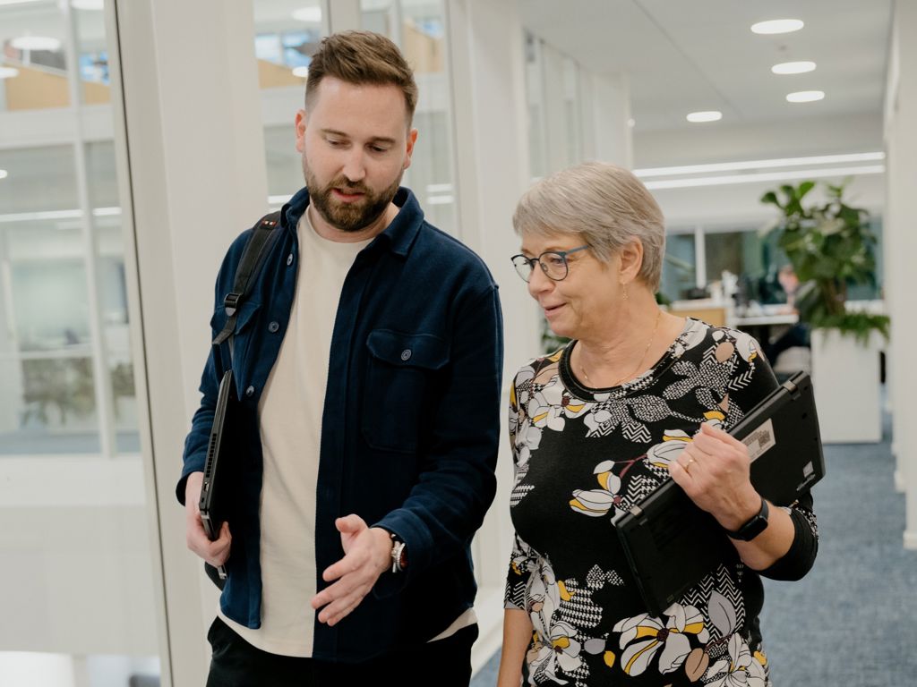 To kollegaer går og snakker på kontorgang