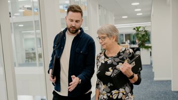 To kollegaer går og snakker på kontorgang