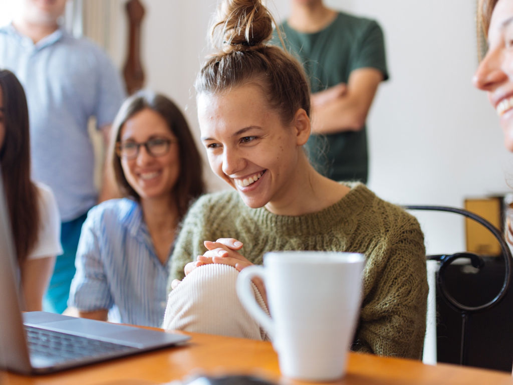 en masse glade mennesker kigger ind i en computer