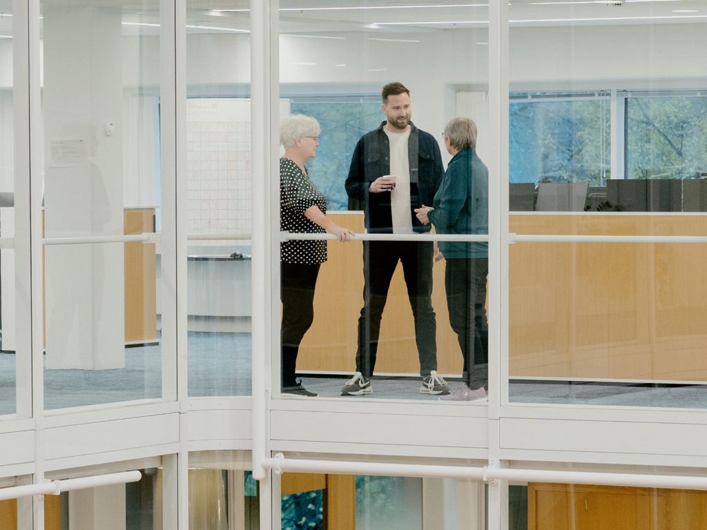 tre mennesker, der står på en svalegang og taler sammen