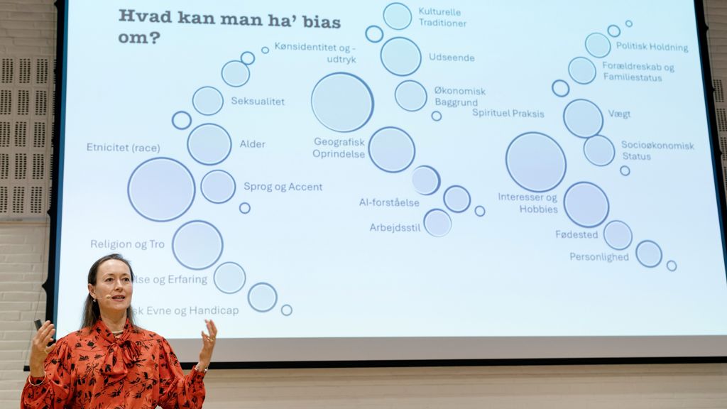 Billede af oplægsholder Signe Biering foran en storskærm der viser et billede af forskellige bias 