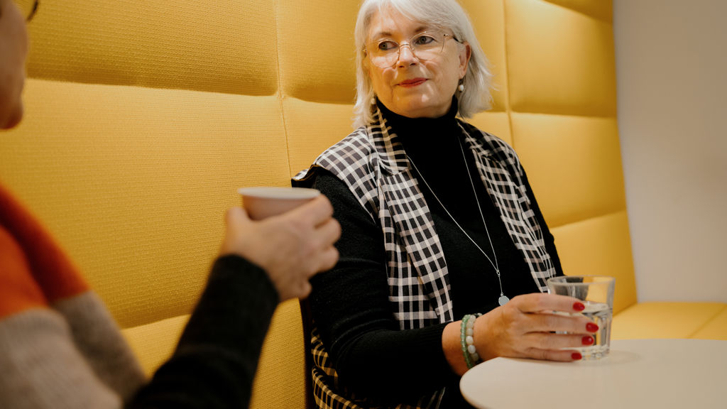 To kvinder sidder i gul sofa med