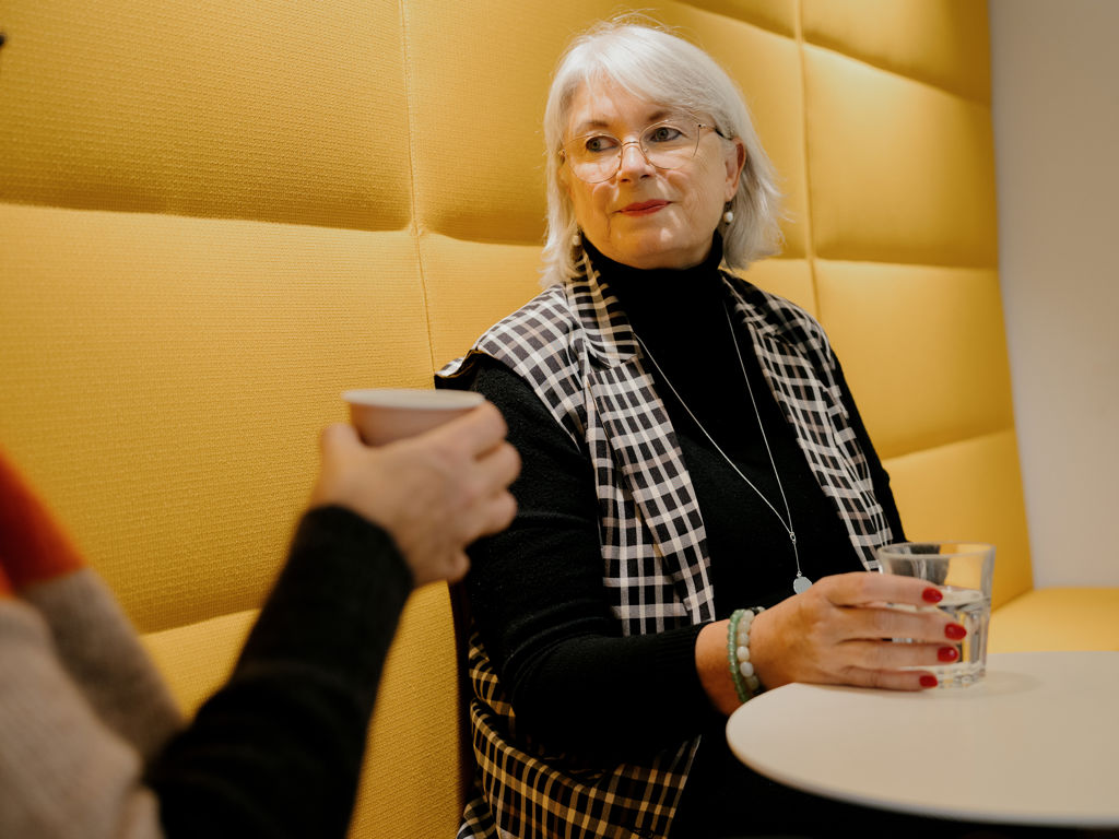 To kvinder sidder i gul sofa med