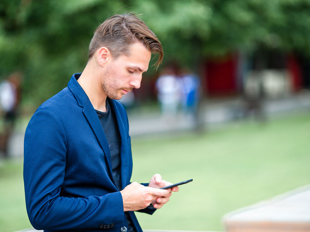 mand kigger på sin telefon ude i naturen
