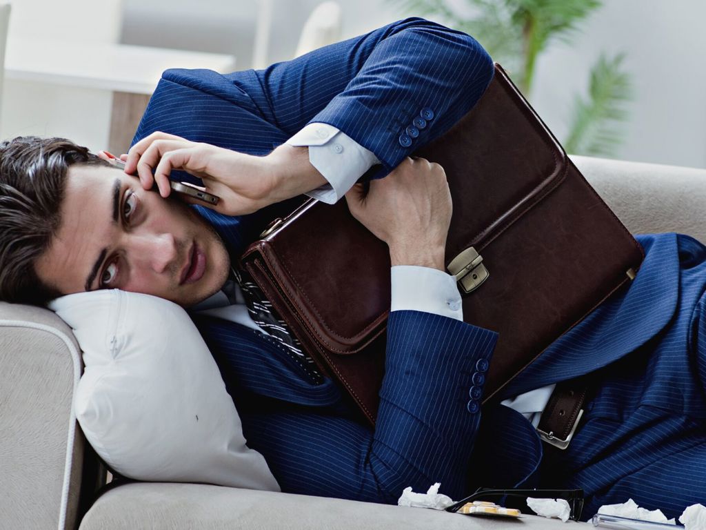 mand der taler i telefon i sofa samtidigt med, at han er syg