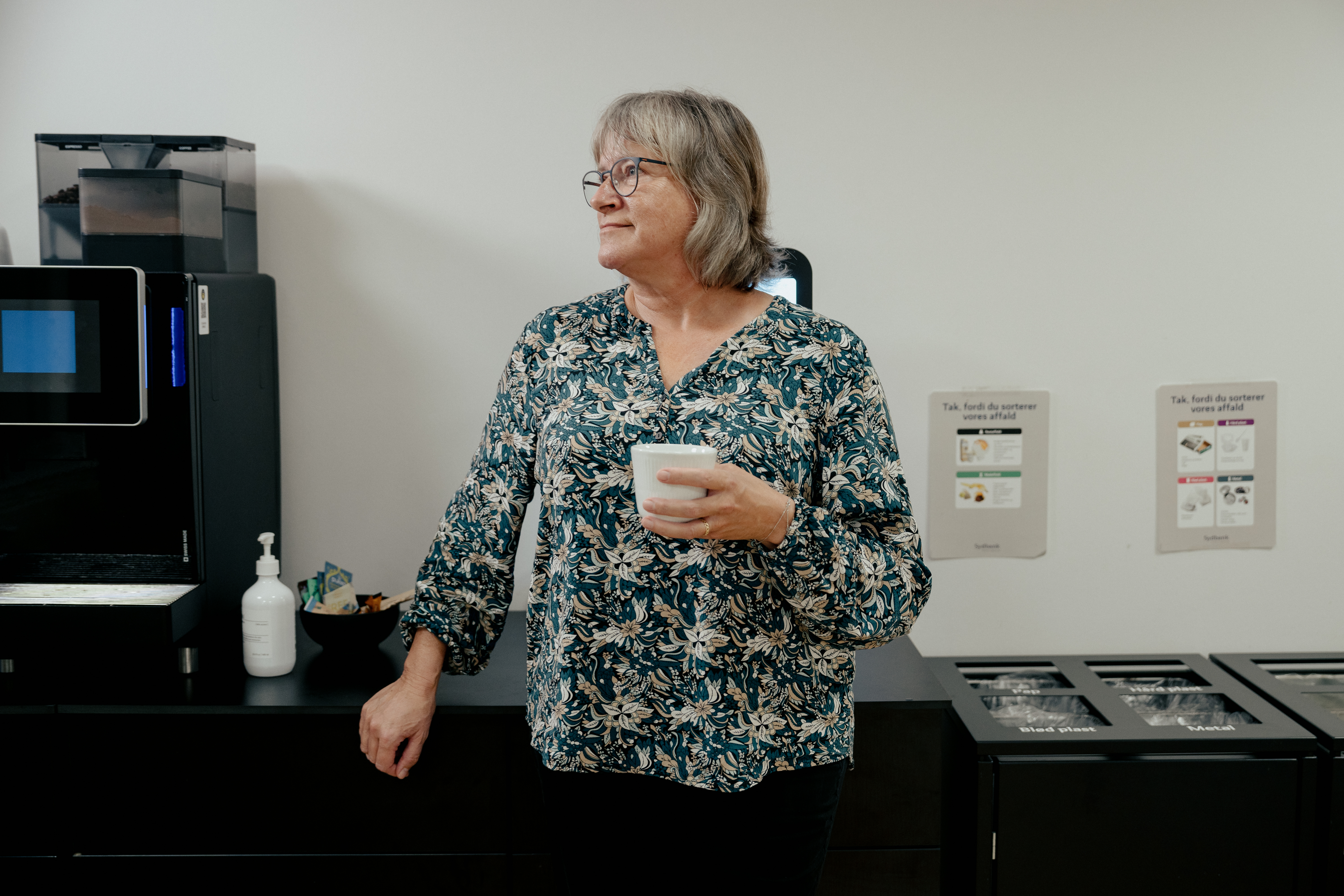 ældre kvinde står med en kop kaffe